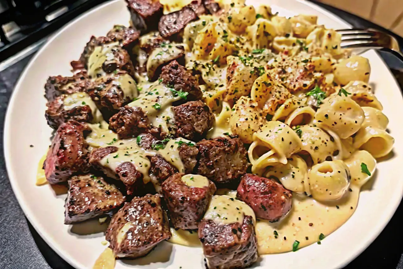 A deliciously plated dish featuring tender Garlic Butter Steak Bites paired with creamy, cheesy Parmesan Shells , garnished with fresh parsley.