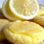 A plate of golden Lemon Poundcake Cookies dusted with powdered sugar, accompanied by fresh lemon slices and mint leaves