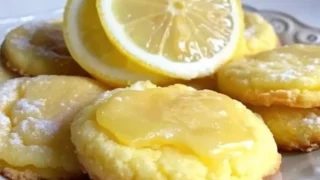 A plate of golden Lemon Poundcake Cookies dusted with powdered sugar, accompanied by fresh lemon slices and mint leaves