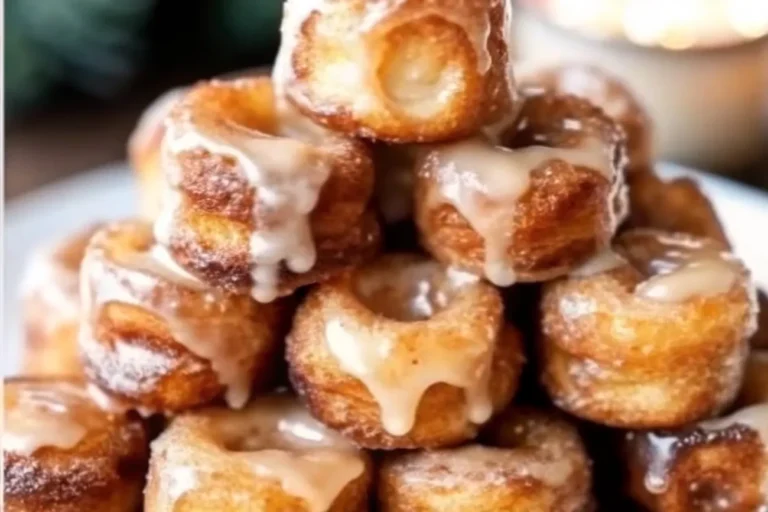 A plate of Cinnamon Roll French Toast Bites with powdered sugar and maple syrup drizzles.