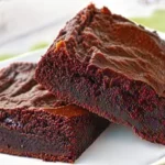 A tray of Vegan Sweet Potato Brownies with a sprinkle of powdered sugar and fresh raspberries.