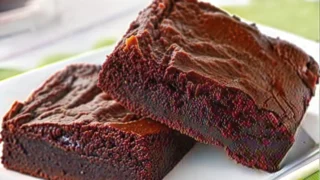 A tray of Vegan Sweet Potato Brownies with a sprinkle of powdered sugar and fresh raspberries.