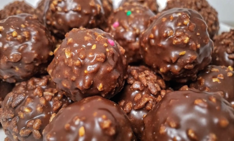 Finished chocolate rice krispie balls arranged on a white serving platter, showing glossy chocolate coating and perfect round shapes