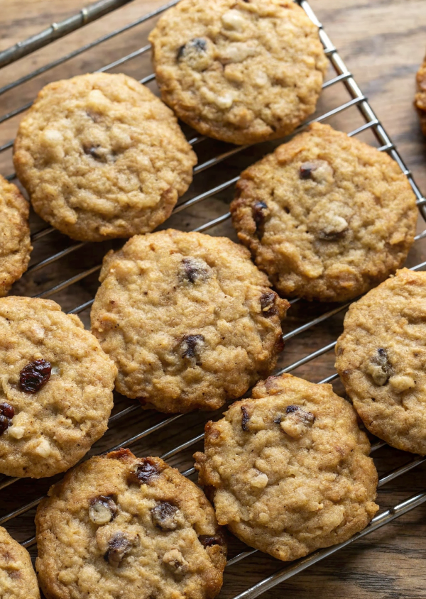 Stack of golden brown oatmeal raisin cookies on a white plate with a glass of milk in the background