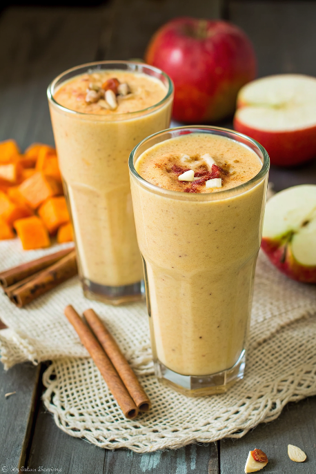 Finished pumpkin apple smoothie in tall glasses garnished with cinnamon and served on rustic wooden table