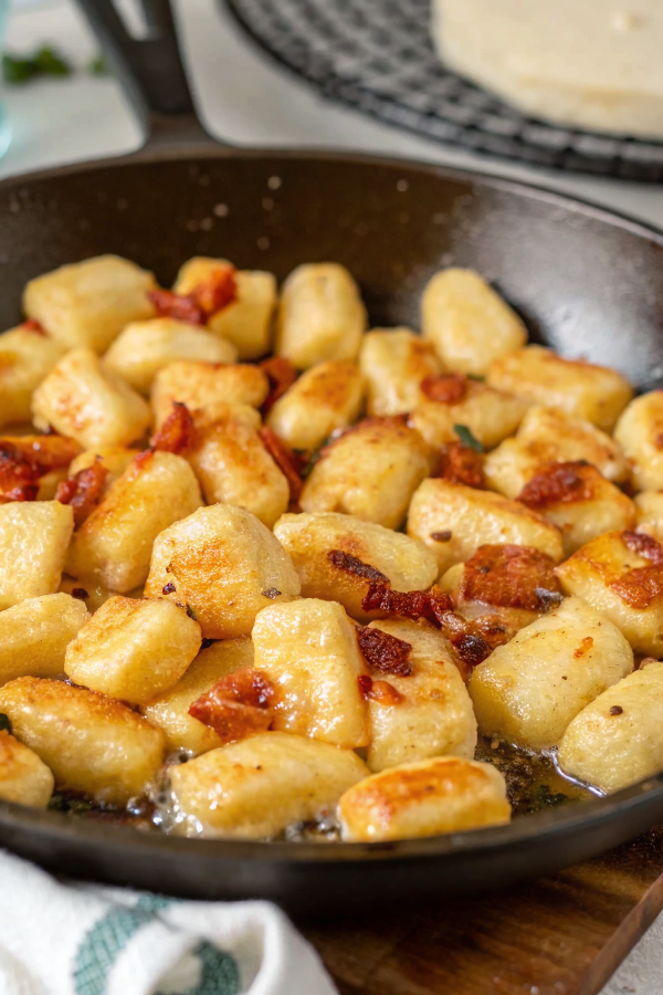 Perfectly cooked ricotta gnocchi served in a white bowl with marinara sauce, fresh basil, and grated Parmesan cheese