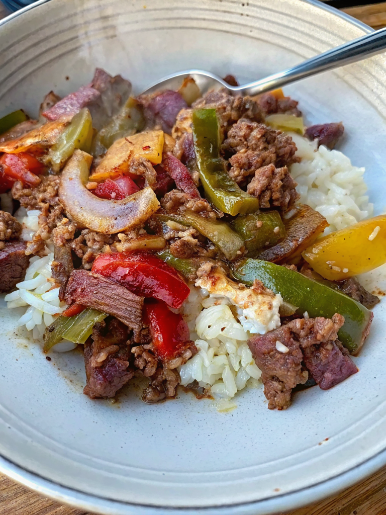 Finished Beef and Peppers Skillet served over fluffy white rice in a beautiful bowl, garnished with green onions and sesame seeds