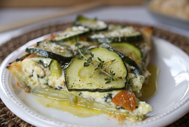 Golden-brown Boureki casserole fresh from the oven showing beautiful layers of potatoes, zucchini, and melted cheese with fresh herbs on top