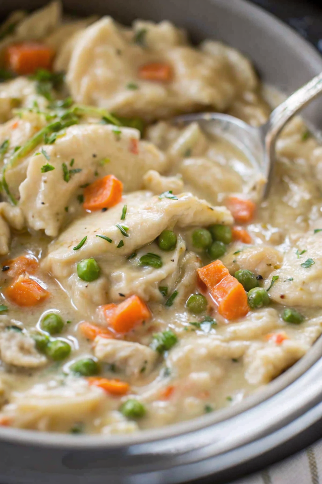 Beautiful finished bowl of Crock Pot Chicken and Dumplings with golden dumplings floating on creamy base garnished with fresh parsley