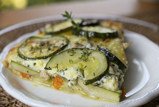 Finished Boureki casserole with golden-brown top, perfectly layered vegetables, and fresh herb garnish on elegant white serving platter