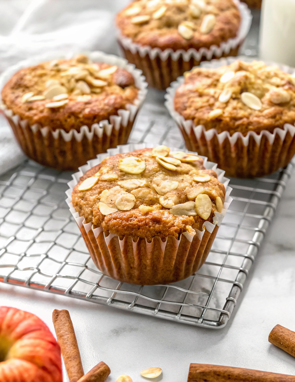 Finished healthy apple oat muffins on a cooling rack with golden brown tops and visible oat pieces, ready to serve