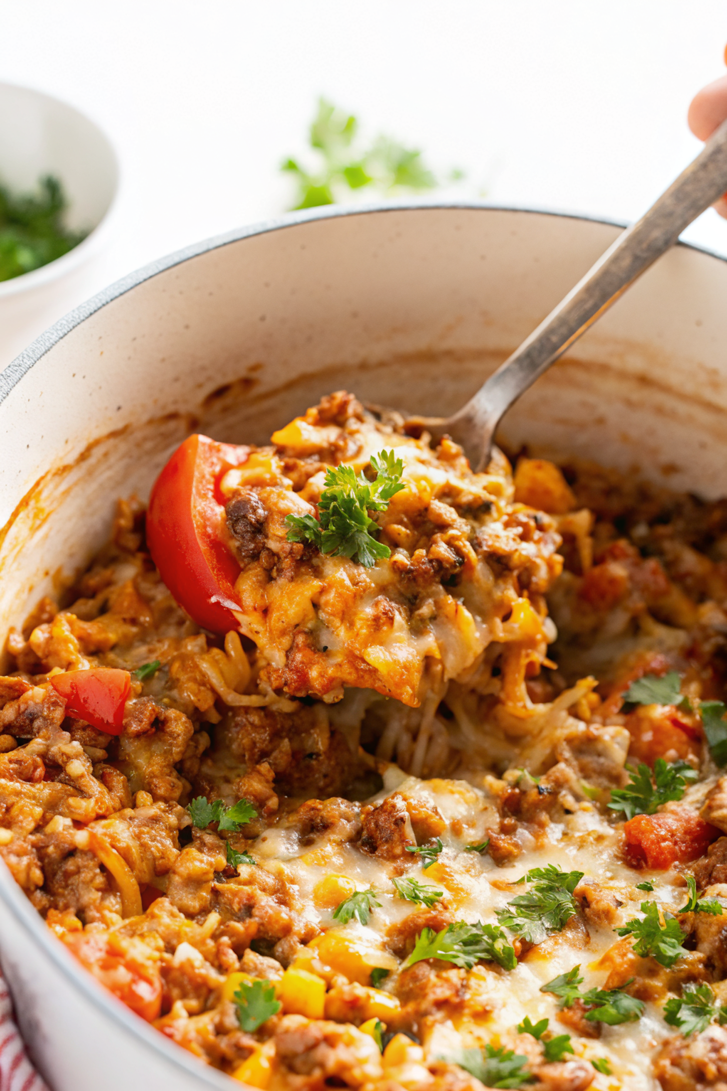 Finished stuffed pepper casserole served in a rustic cast iron pot with melted cheese golden and bubbly on top, surrounded by colorful bell pepper pieces