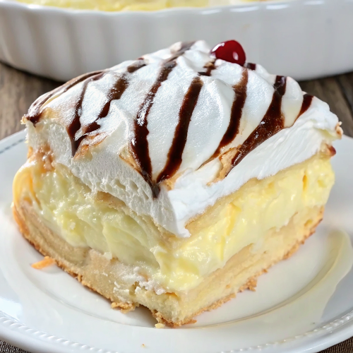 Beautifully presented cream puff cake slice on white plate showing distinct layers of golden choux pastry, vanilla cream, and chocolate drizzle