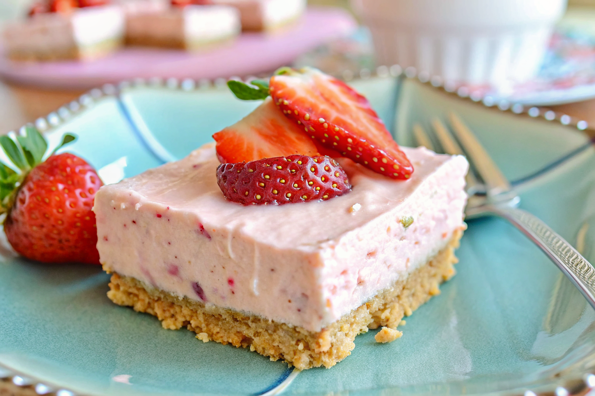 Beautiful finished no-bake strawberry cheesecake bars arranged on elegant serving platter with fresh strawberry garnish and perfect presentation
