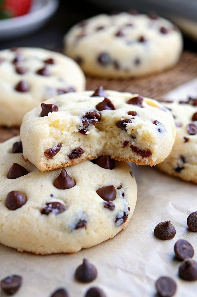 Finished chocolate chip cheesecake cookies arranged on a white plate with a glass of milk in the background