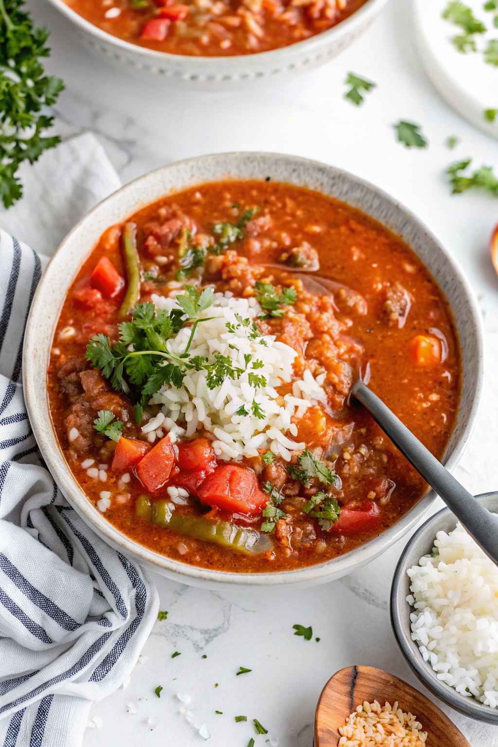 A steaming bowl of Easy Stuffed Pepper Soup with Rice garnished with fresh herbs and served with crusty bread on a rustic wooden table