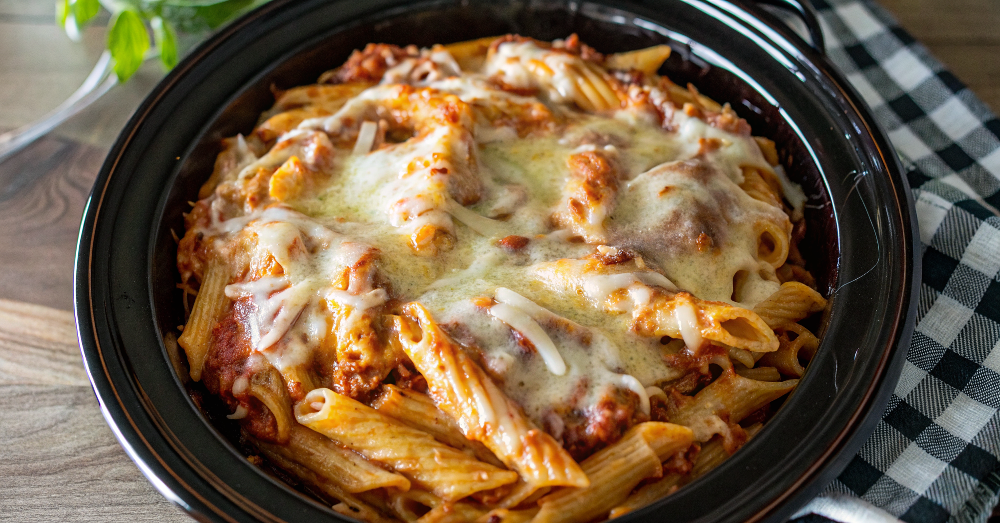 Beautiful finished slow cooker chicken parmesan pasta served in white bowl with fresh parsley garnish