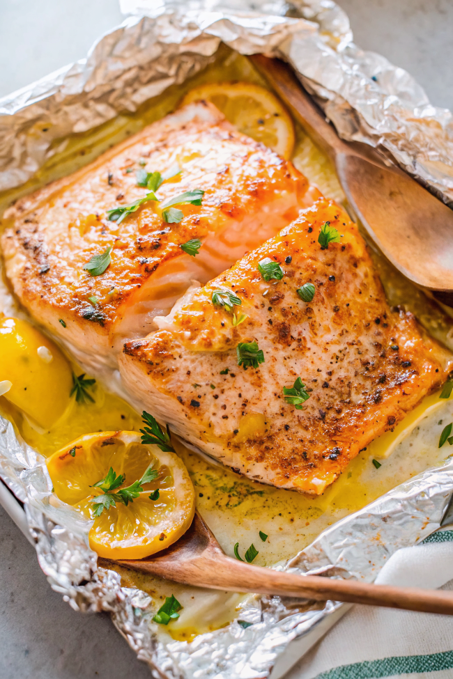 Perfectly cooked sheet pan lemon garlic butter salmon with golden edges, surrounded by caramelized lemon slices and fresh herbs