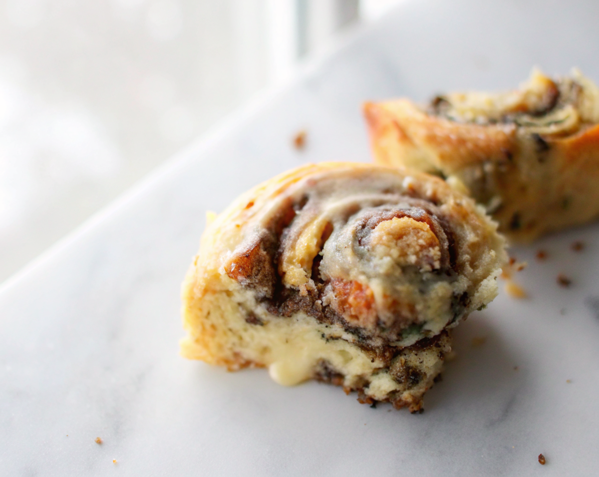 Golden brown chocolate peanut butter cinnamon rolls with creamy frosting drizzled on top, served on a rustic wooden board