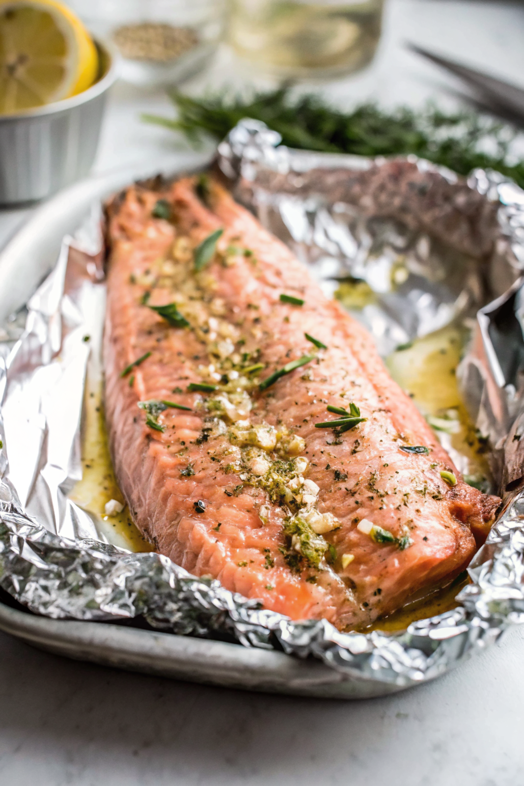 Beautifully cooked garlic butter baked salmon in foil garnished with fresh parsley and lemon wedges